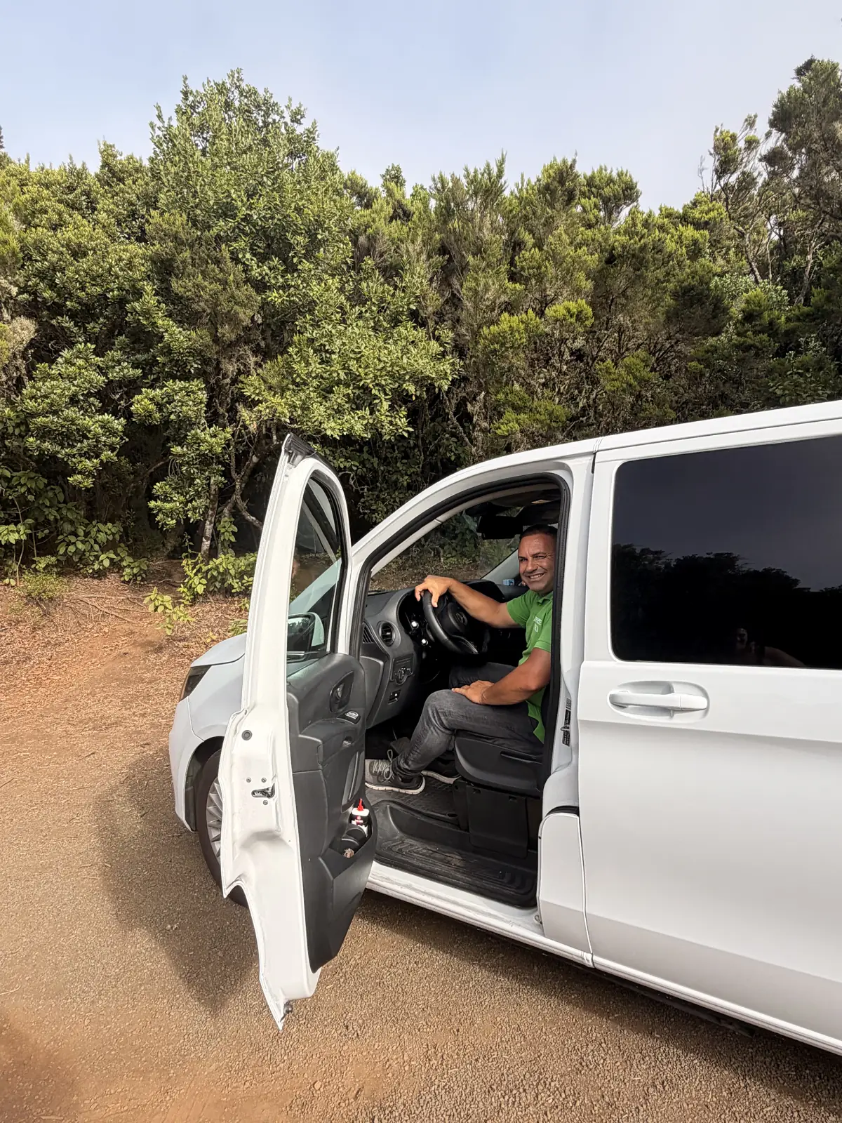 Fernando al volante del taxi, con la puerta abierta, en una pista del monte de La Gomera